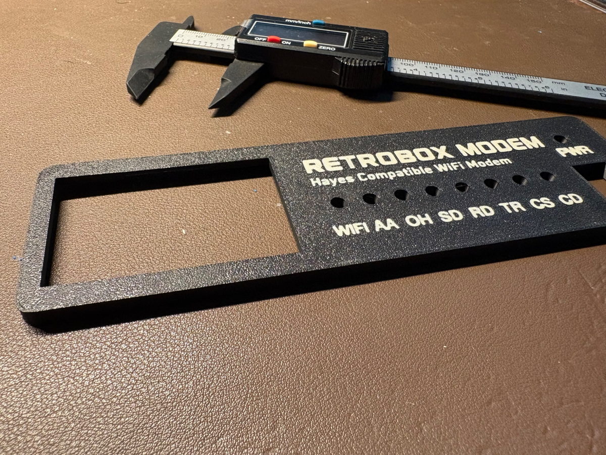 Frontal de RetroBox Modem impreso en 3D junto a un calibre digital durante las pruebas de ajuste y tolerancias.